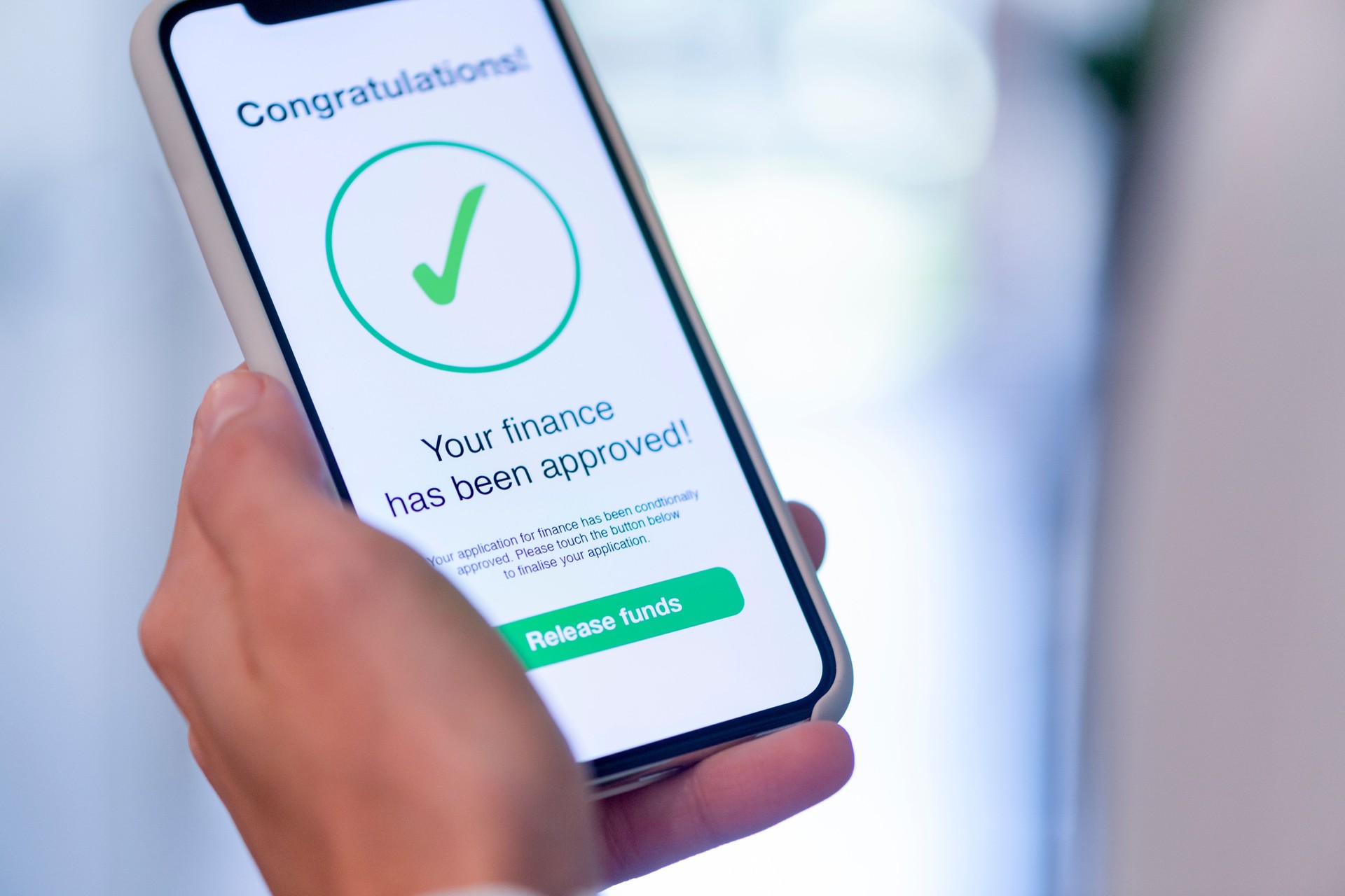 Woman holding a mobile phone with loan application approval.